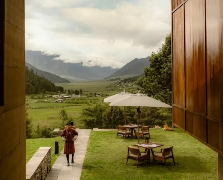 Luxury lodge terrace overlooking green Himalayan valley with outdoor dining tables and scenic mountain landscape travel experience.