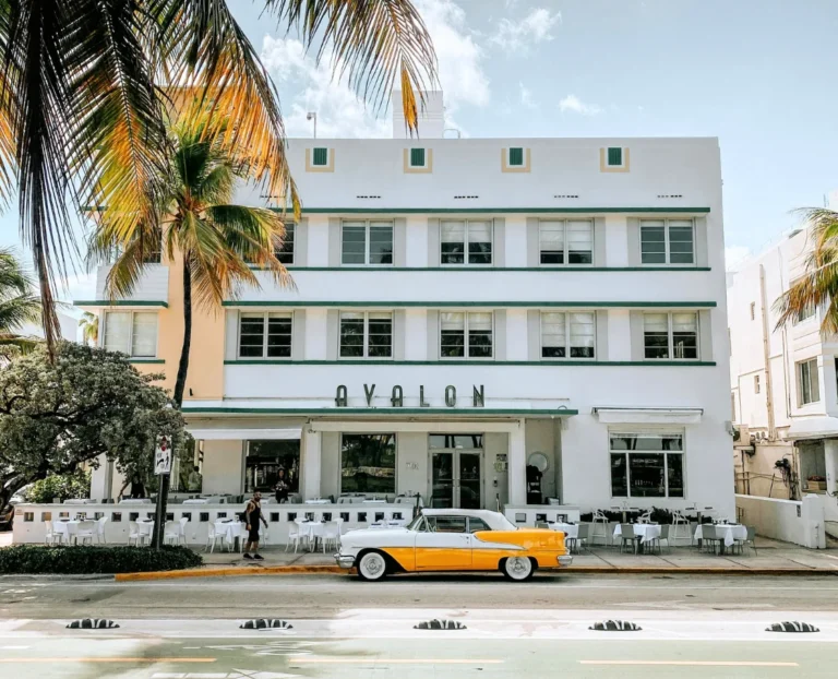 Avalon Hotel Miami Beach art deco building with vintage yellow car and palm trees on Ocean Drive, iconic boutique hotel architecture in South Beach.