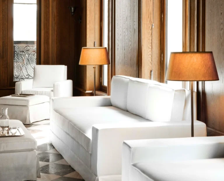 Luxury boutique hotel lounge with white sofa seating, warm lighting and elegant minimalist interior design for premium travel stays.