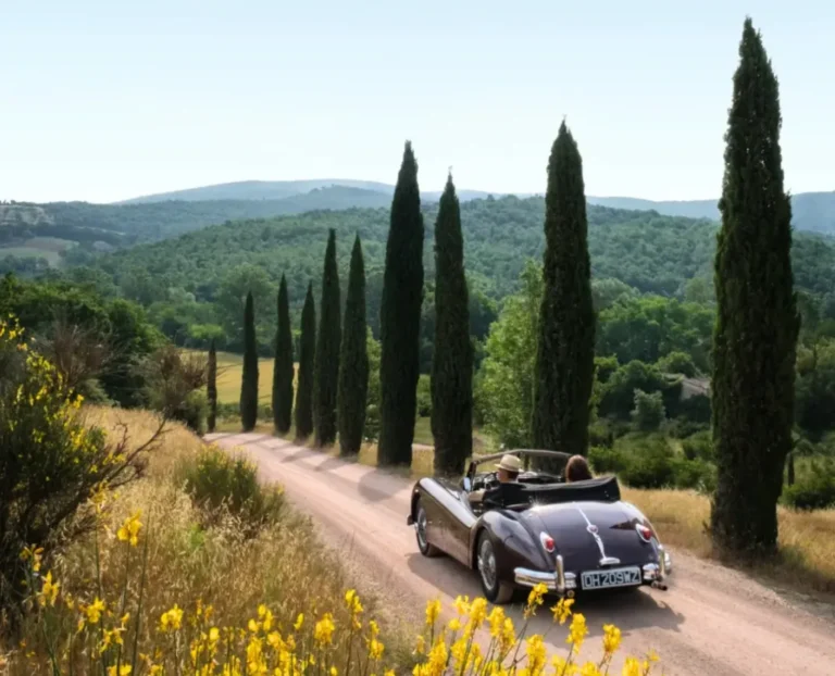 Vintage convertible driving through cypress tree road in Tuscany countryside, romantic Italian road trip and luxury travel experience.