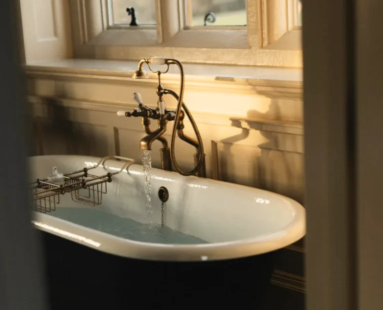 Vintage freestanding bathtub in elegant luxury hotel bathroom with warm sunset light and classic interior design atmosphere.
